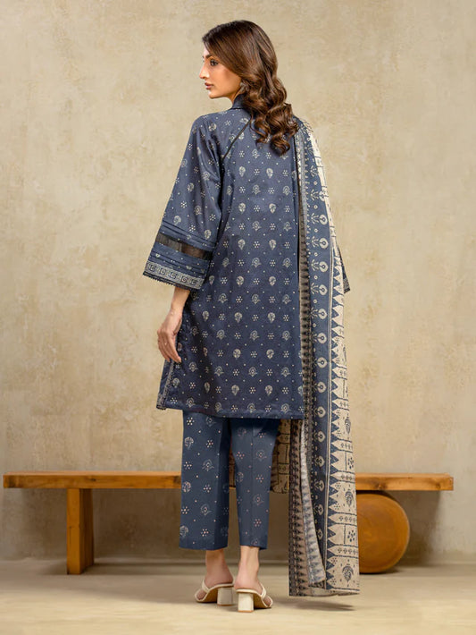 Woman wearing a blue traditional outfit with a patterned dupatta against a beige wall.