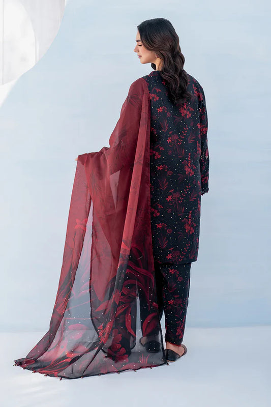 Woman wearing a black and red floral outfit with a matching dupatta against a light blue background