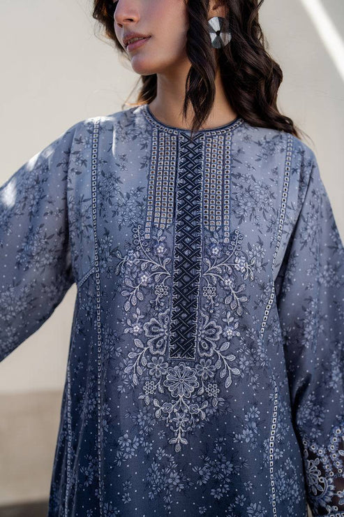 Woman wearing a blue embroidered traditional outfit with a neutral background