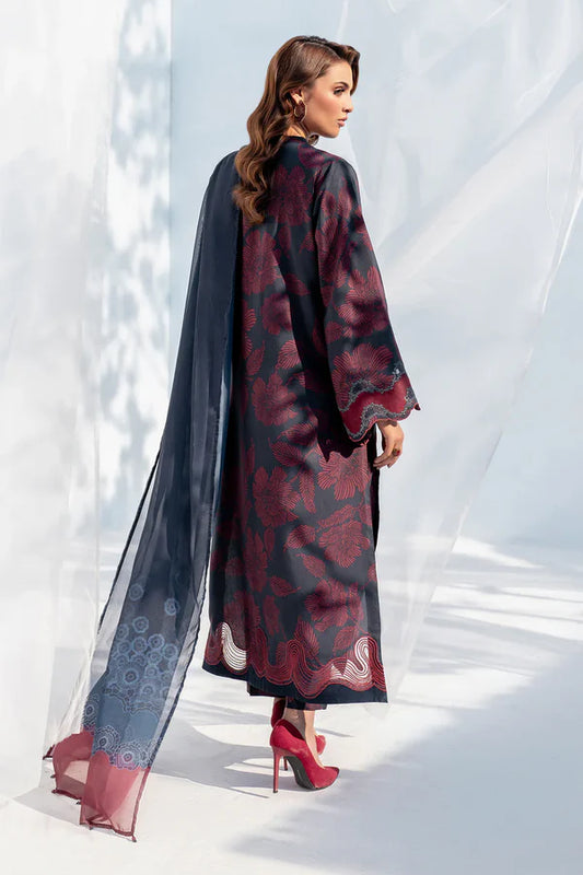 Woman wearing a long, patterned dress with a sheer overlay against a white background