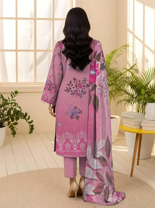 Woman in a pink embroidered outfit standing in a bright room with plants.