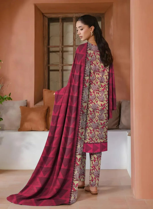 Woman in a traditional outfit with a pink and patterned design standing in a room with a couch and window.