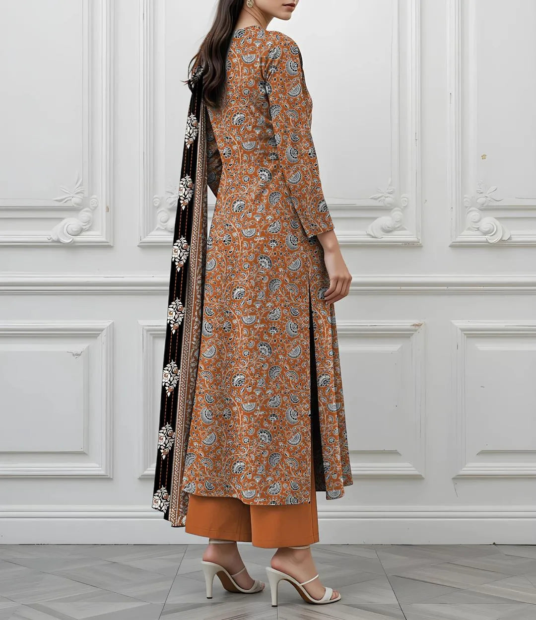 Woman wearing a patterned brown outfit with a black scarf against a white paneled wall.