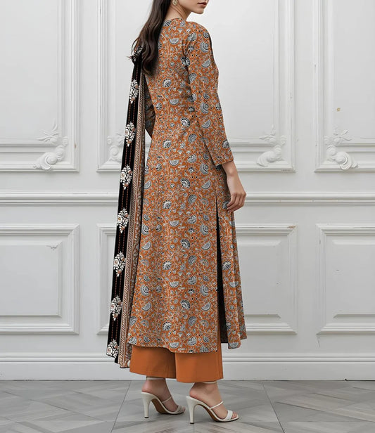 Woman wearing a patterned brown outfit with a black scarf against a white paneled wall.