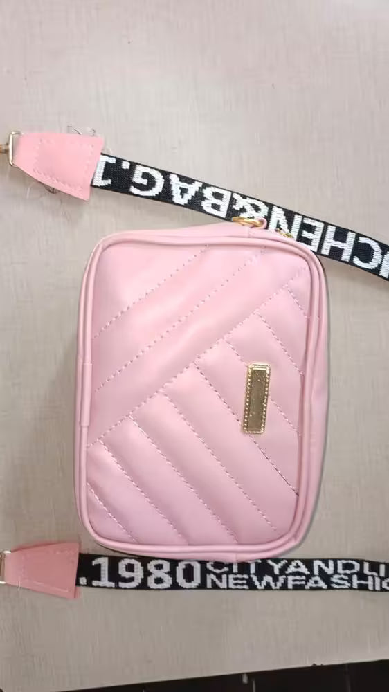 Pink quilted pouch with a strap on a light gray background