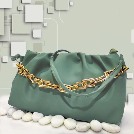 Green handbag with gold chain detail on a light gray background