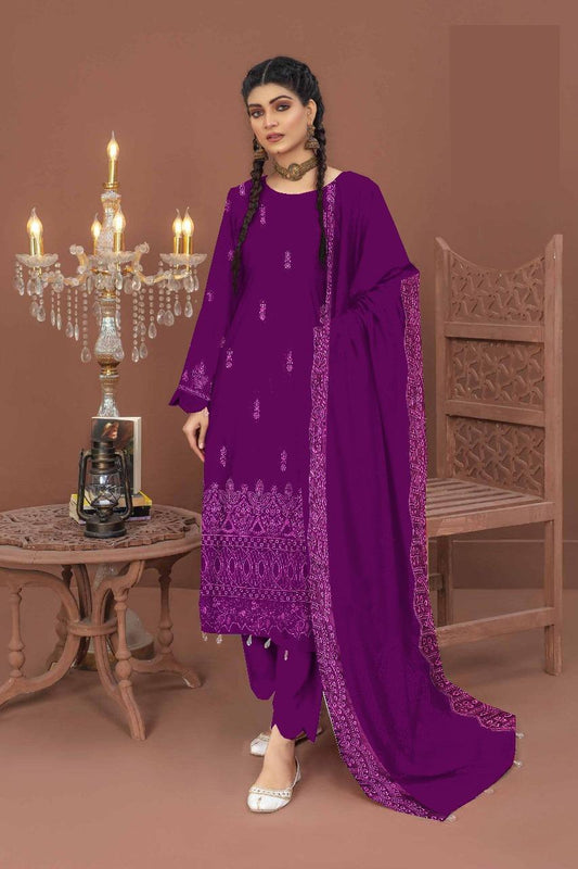 Woman in a purple traditional outfit standing in a room with a chandelier and wooden furniture.