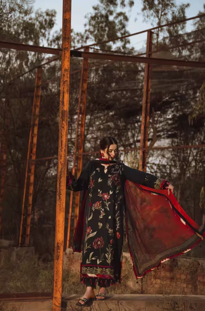 Woman in a floral dress holding a red scarf in an industrial setting