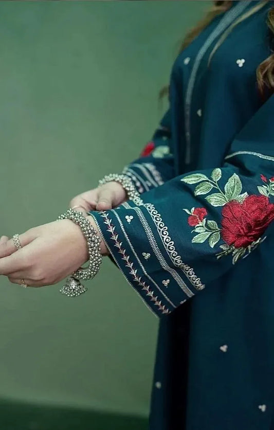 Close-up of a person wearing a dark blue embroidered garment with red flowers on a green background