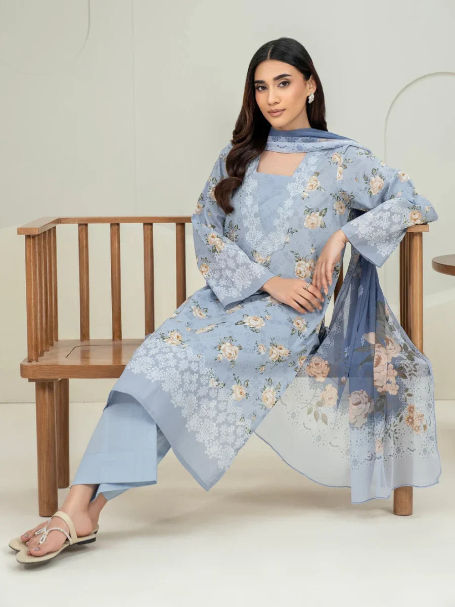 Woman wearing a light blue floral outfit with a matching dupatta, sitting on a wooden chair.