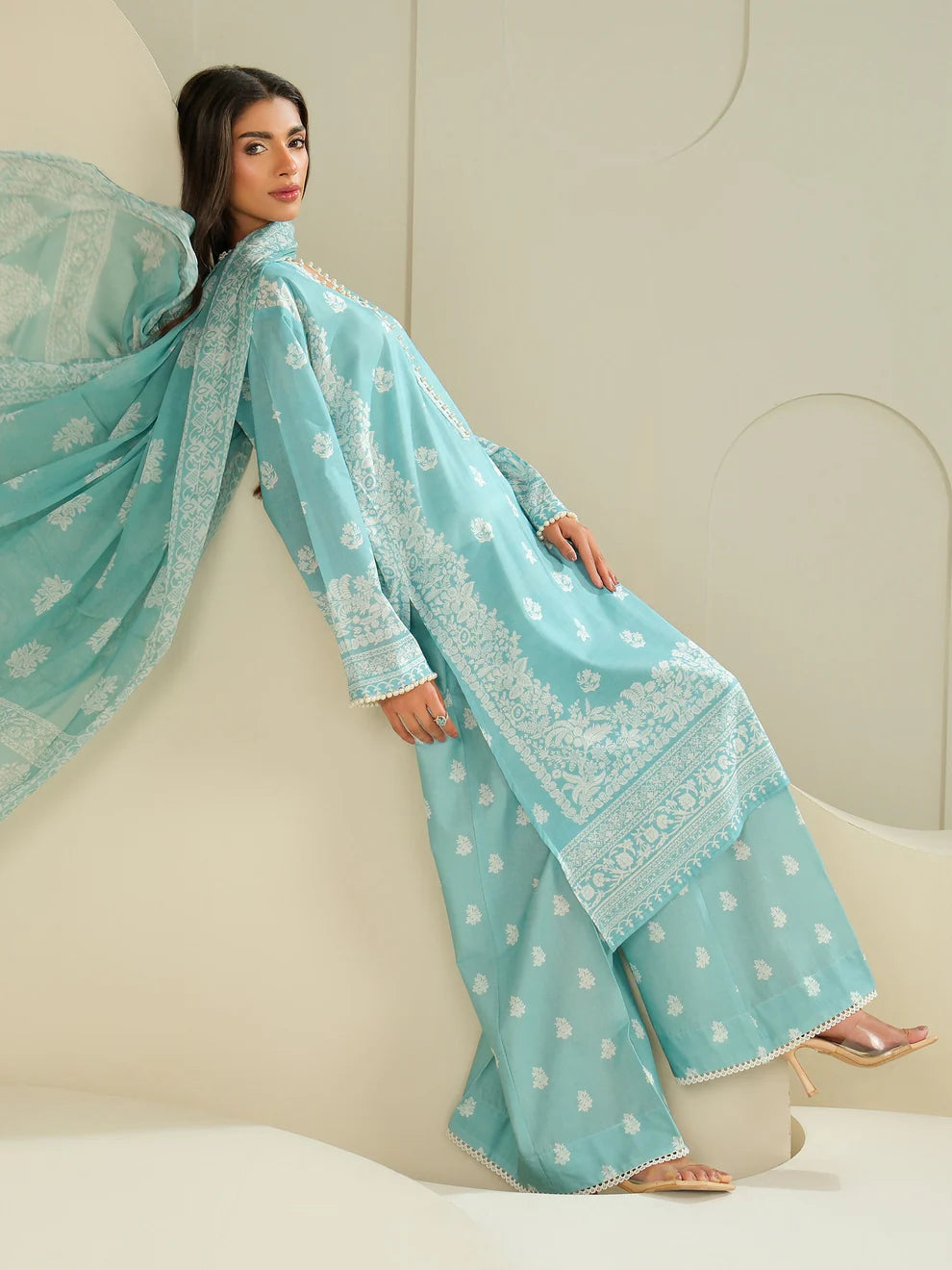 Woman wearing a light blue embroidered traditional outfit with a matching dupatta on a neutral background
