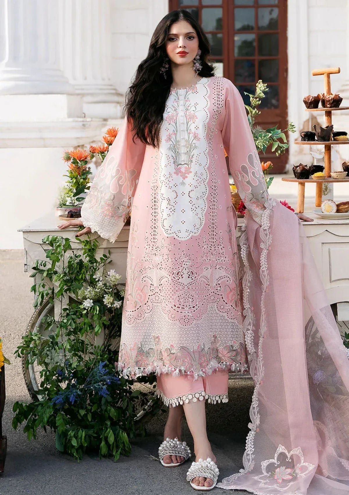 Woman wearing a pink embroidered dress with a white background