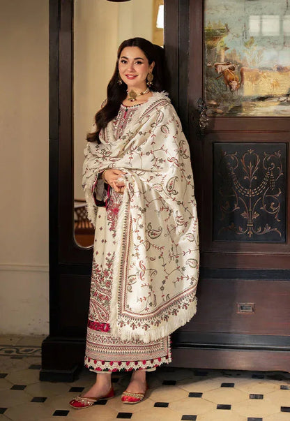 Woman in traditional embroidered outfit standing indoors next to a decorative cabinet.