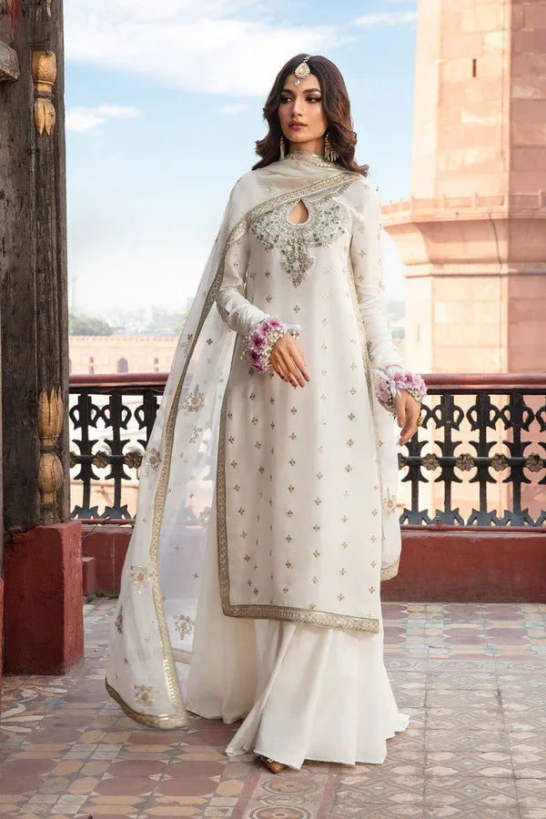 Woman in a white traditional outfit with intricate designs standing in front of a historical building.