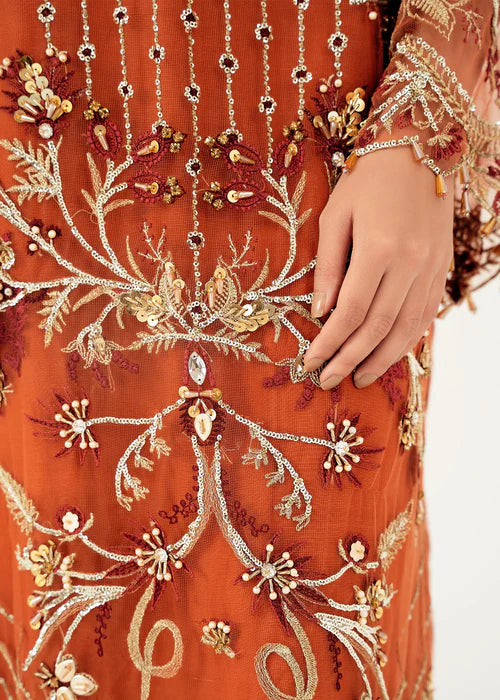 Close-up of an orange embroidered garment with intricate patterns and embellishments.