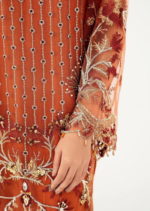 Close-up of an orange embroidered garment with intricate patterns on a white background