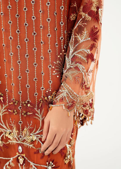 Close-up of an orange embroidered garment with intricate patterns on a white background