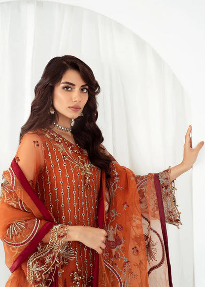Woman wearing an orange embroidered traditional outfit with a white background