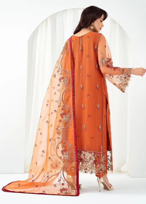 Woman wearing an orange embroidered outfit with a sheer dupatta on a white background
