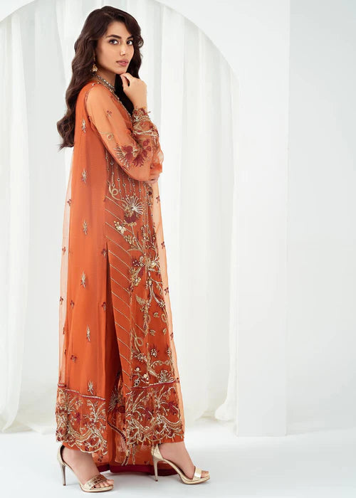 Woman wearing an orange embroidered outfit with a white background