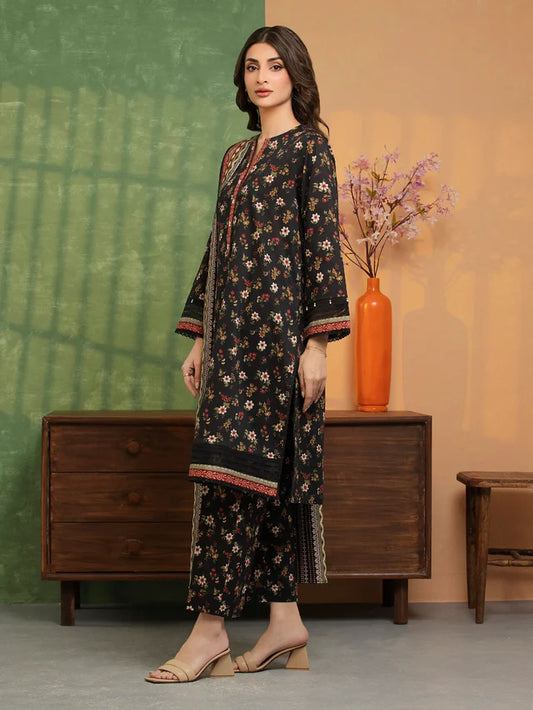 Woman in a floral dress standing in front of a wooden dresser with a vase and flowers.