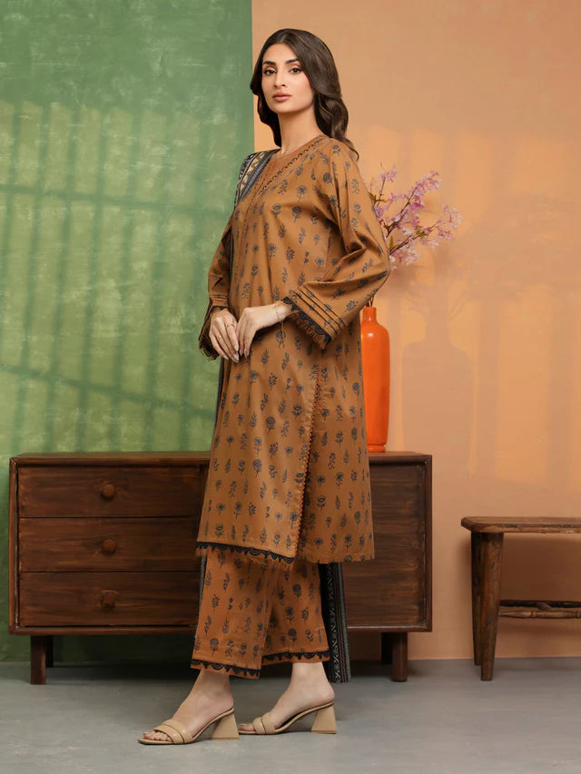 Woman wearing a brown patterned outfit standing in a room with a wooden dresser and decorative elements.
