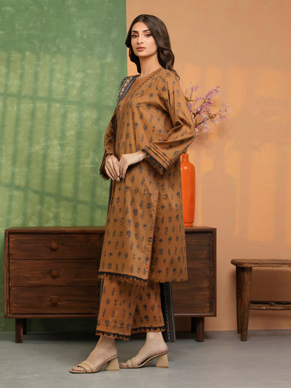 Woman wearing a brown patterned outfit standing in a room with a wooden dresser and decorative elements.