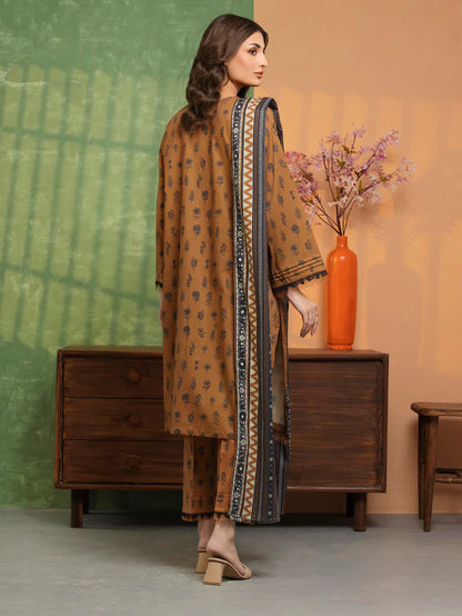 Woman in a brown traditional outfit standing in a room with a wooden dresser and decorative vase.