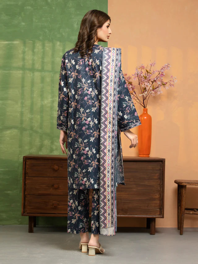 Woman in a floral dress with a patterned scarf standing in a room with a wooden dresser and vase.