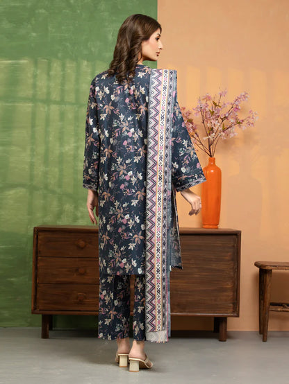 Woman in a floral dress with a patterned scarf standing in a room with a wooden dresser and vase.