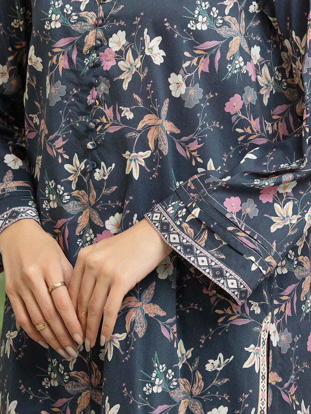 Close-up of a person wearing a dark floral-patterned outfit with hands resting on the lap.