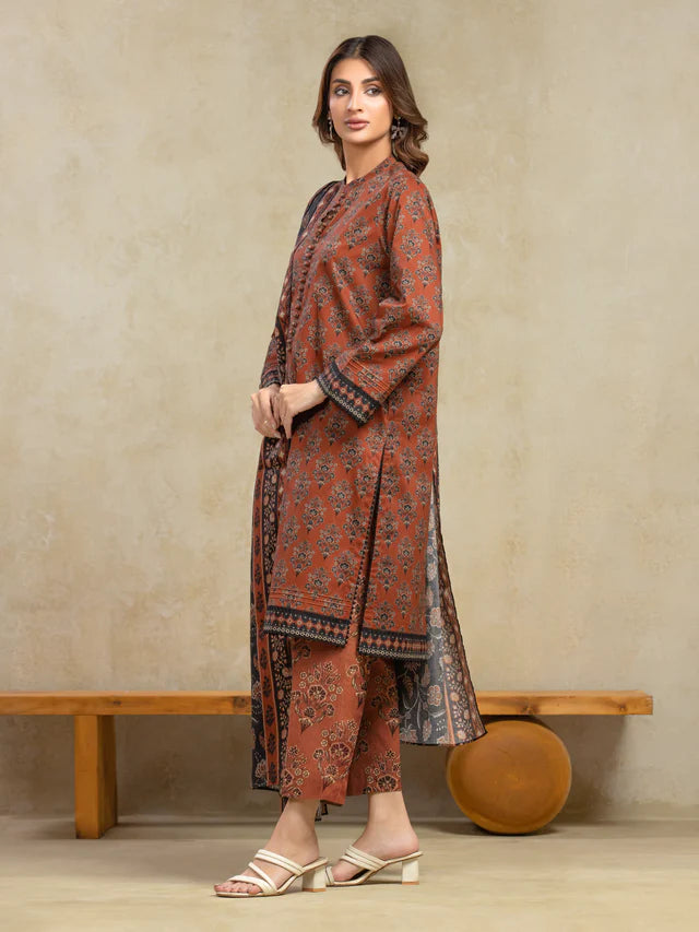 Woman wearing a traditional outfit with a patterned dress and pants against a beige wall.