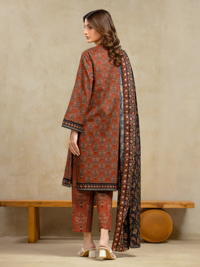 Woman wearing a patterned outfit with a long scarf against a beige wall.