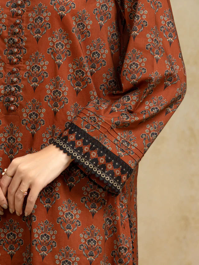 Close-up of a rust-colored garment with intricate black floral patterns on a beige background