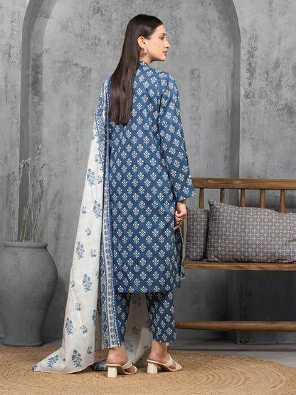 Woman wearing a blue and white traditional outfit with a gray wall and wooden bench in the background