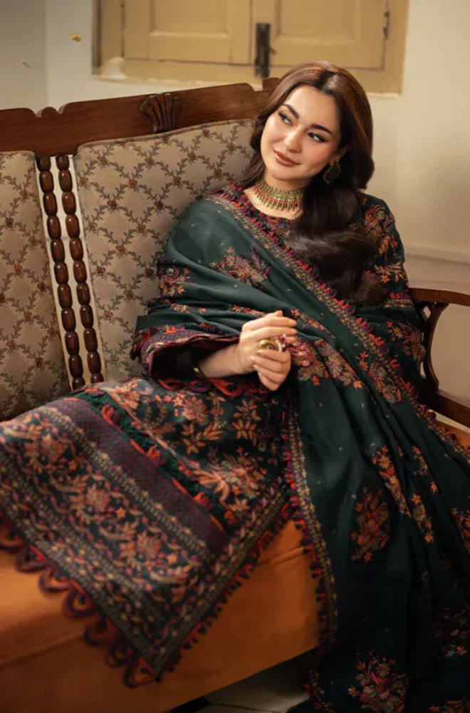 Woman sitting on a patterned chair wearing a dark green floral shawl.