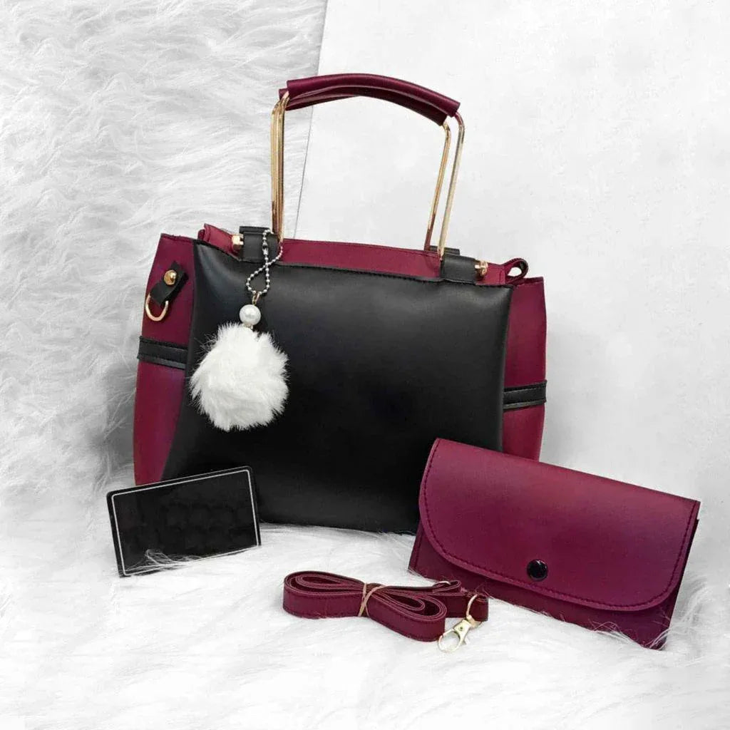 Black and burgundy handbag with matching wallet and strap on a white background