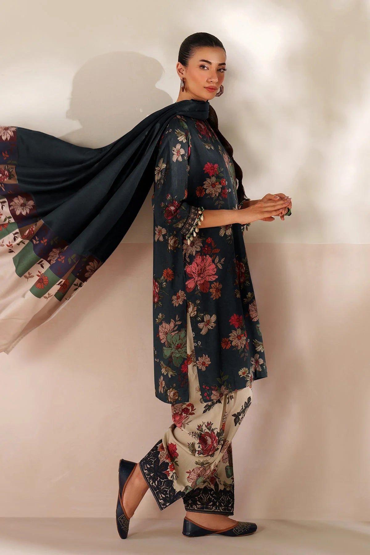 Woman wearing a floral outfit with a dark blue shawl against a plain background