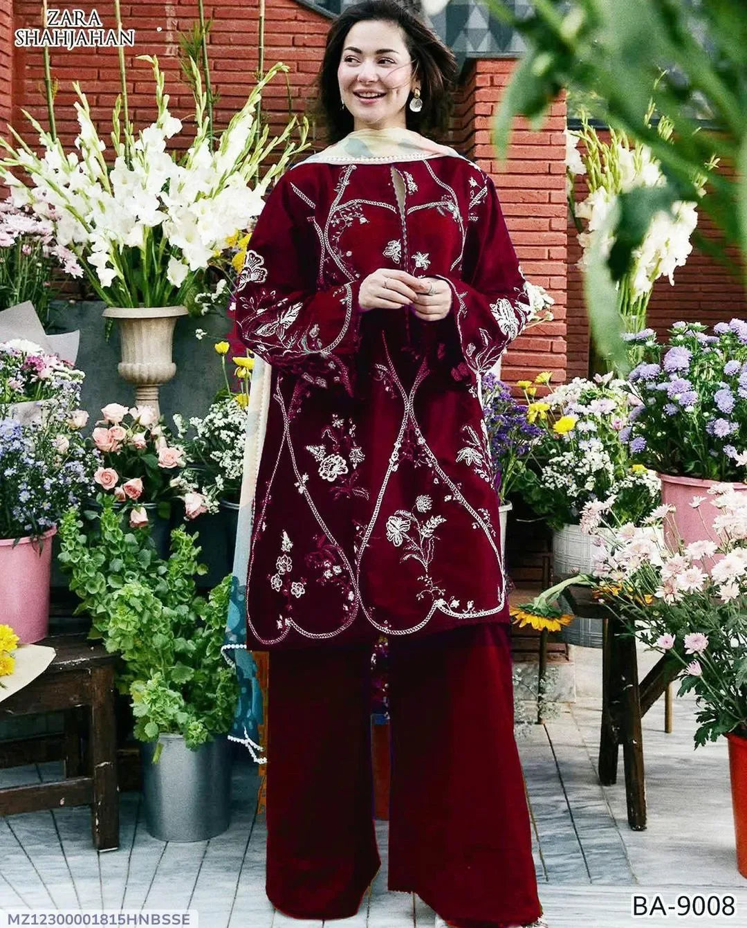 Woman in a burgundy embroidered outfit standing among flowers