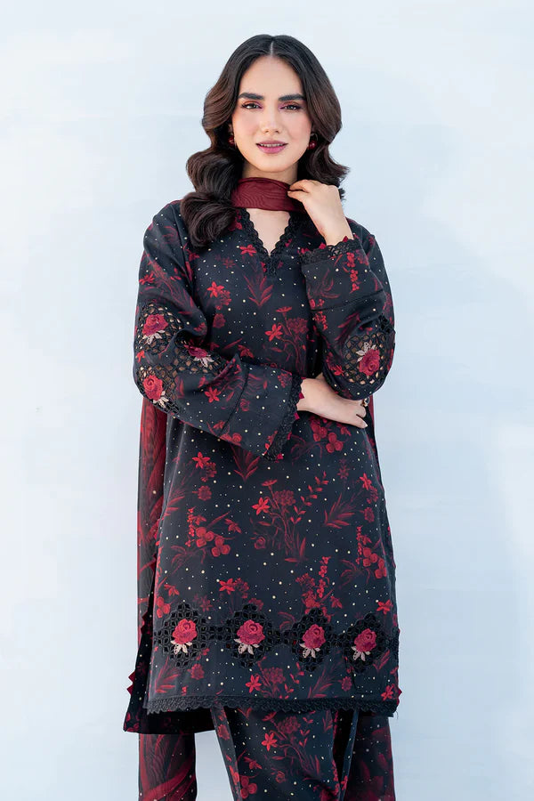 Woman wearing a black floral dress with red patterns against a white background