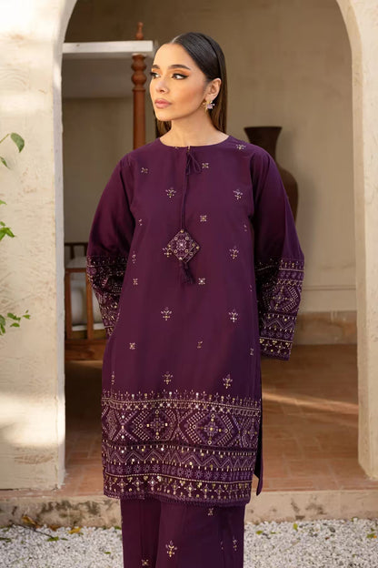 Woman wearing a purple embroidered outfit standing in an outdoor setting.
