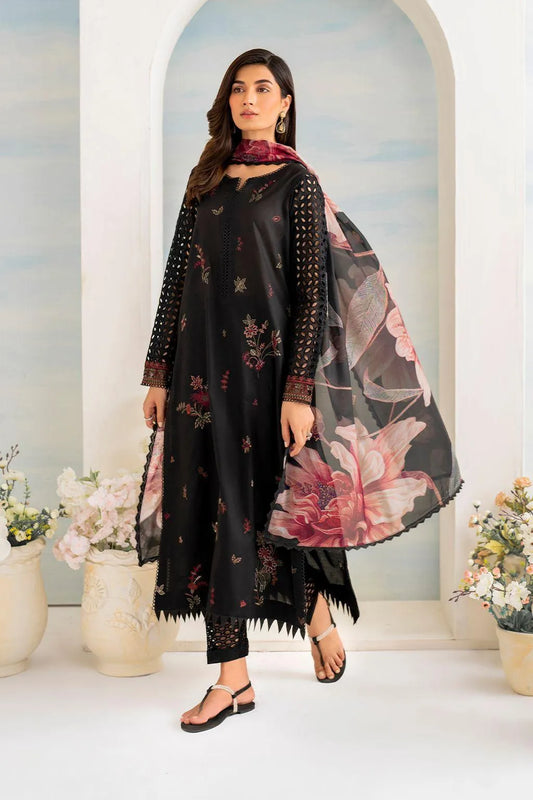 Woman wearing a black floral dress with a matching shawl in a decorated room.
