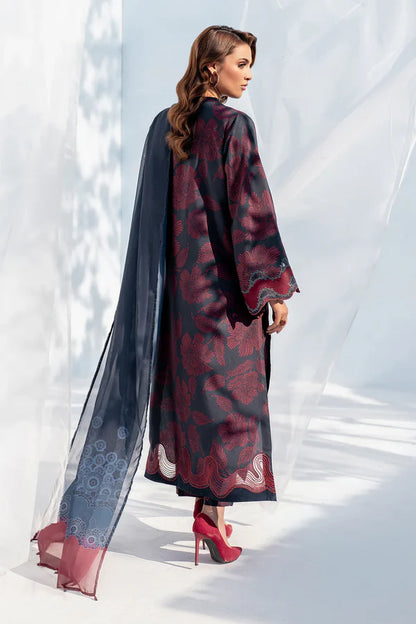 Woman wearing a long, patterned dress with a sheer overlay against a white background