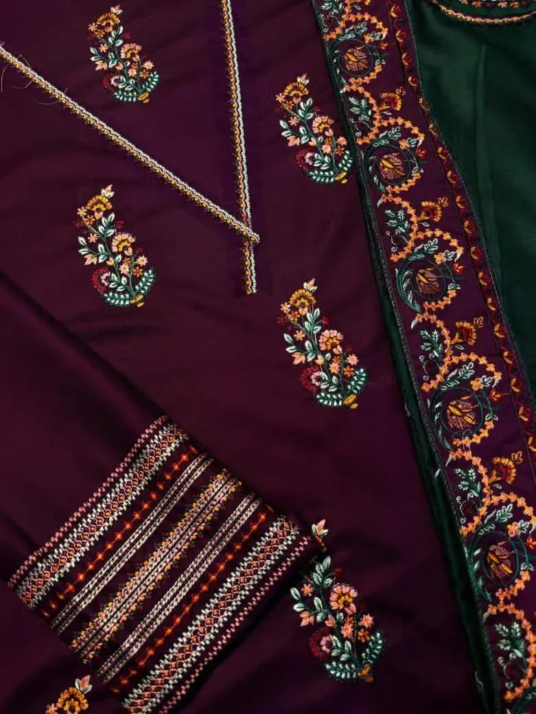 Close-up of a maroon fabric with intricate floral embroidery and a green border.