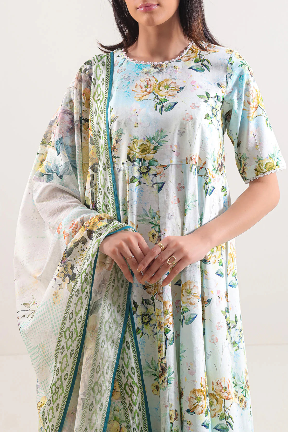 Woman wearing a floral dress with a matching shawl against a white background