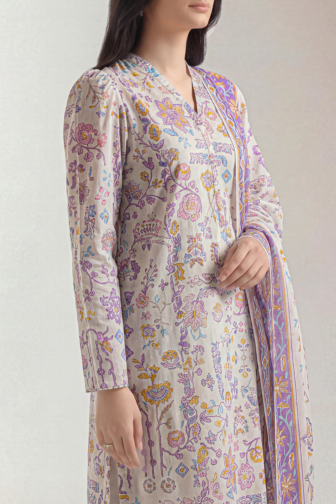 Woman wearing a floral patterned kurta with a matching dupatta on a plain background