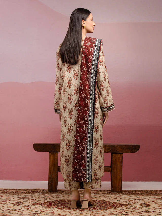 Woman in a floral dress standing in front of a pink wall with a wooden bench.