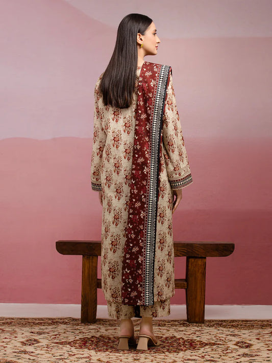 Woman in a floral dress standing in front of a pink wall with a wooden bench.