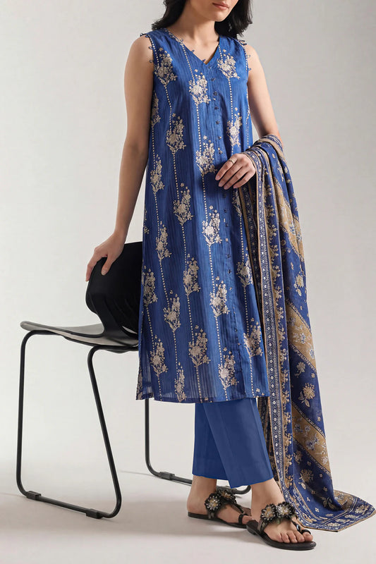 Woman wearing a blue floral dress with a matching dupatta, sitting on a chair against a plain background.