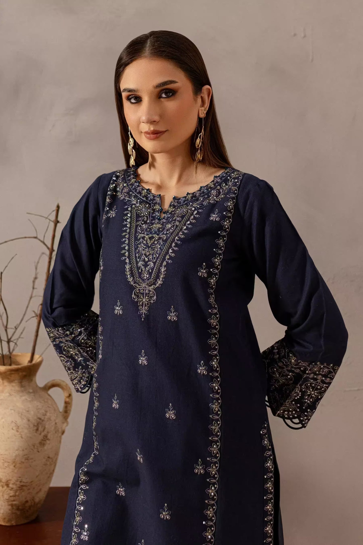 Woman wearing a navy blue embroidered dress against a neutral background